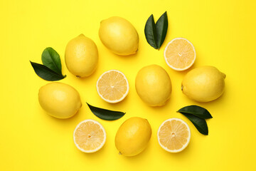 Fototapeta premium Ripe lemons and leaves on yellow background, flat lay