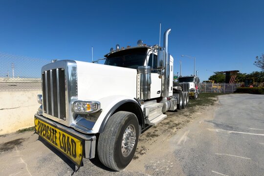 Parked white heavy-duty truck with long hood design used for heavy hauling, with Oversize Load banner
