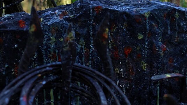 closeup shot of iron bangles and trishul mounted near sacred rock on ground near temple.Sacred trident and bangles close up shot.