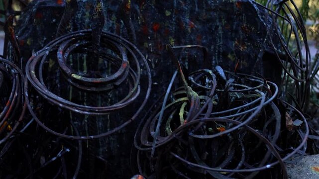 closeup shot of iron bangles and trishul mounted near sacred rock on ground near temple.Sacred trident and bangles close up shot.