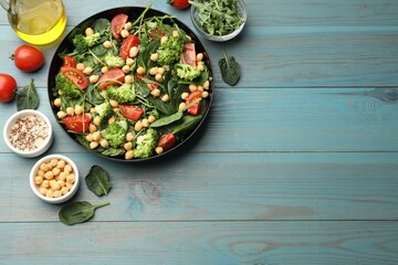 Obraz premium Tasty salad with chickpeas served on light blue wooden table, flat lay. Space for text
