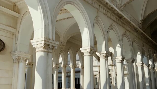Elegant 4K architectural reveal of gallery with white arches and columns bathed soft sunlight featuring high quality zoom effect to highlight sophisticated structural beauty