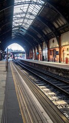 Obraz premium Train tracks and station with arched roof and sky visible, stretching into the distance