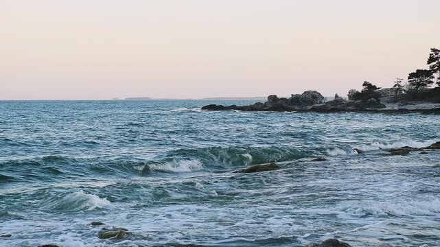 Slow motion waves moving along rocky coastline at Folhammar in Gotland, Sweden with shoreline and trees in background