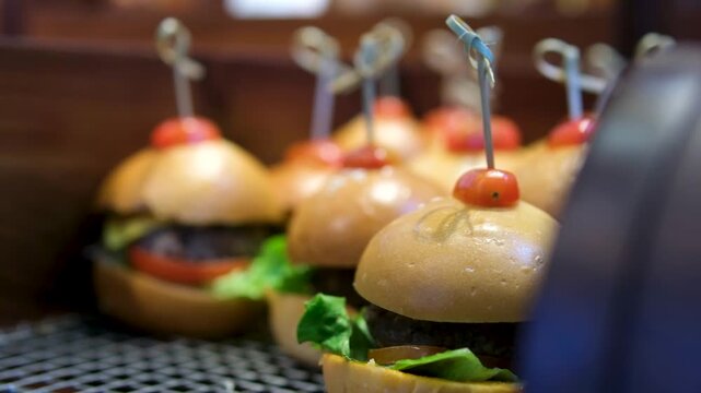 Small burgers with lettuce ham cherry tomato on skewers on a catering tray