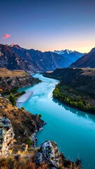 Obraz premium Serene turquoise river winds through rocky mountains during a colorful sunset