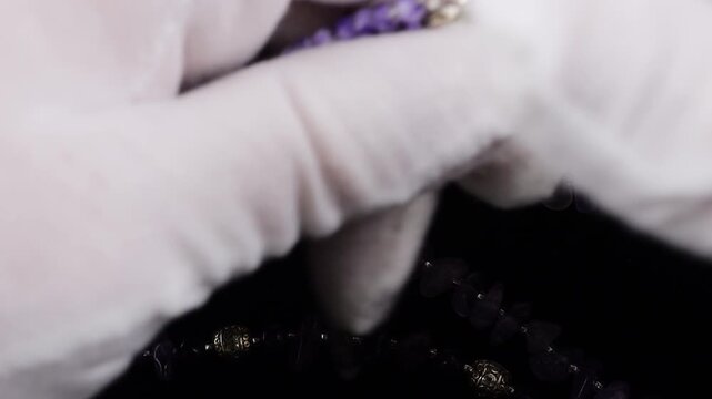 Rows of natural amethyst chip bead necklaces showing vibrant purple hues and silver spacers. Macro view of polished semi-precious stone textures on a black background.