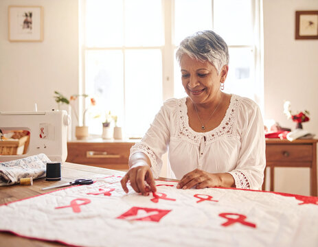 Smiling senior woman handcrafting a quilt with red awareness ribbons. An inspiring image symbolizing health advocacy, charity, and community support in a bright, home studio setting.