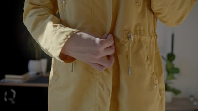 Closeup of woman hands pulling zipper on yellow jacket over black top and jeans. Concept of daily dressing routine and outerwear preparation