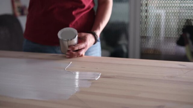 Woman Painting A Wooden Surface With A Brush And Paint From A Tin Can