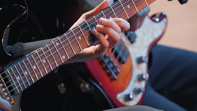Close-up of a musician playing an electric guitar during a concert. Focus is on the hand and fretboard, with warm stage lighting. The background is softly blurred, creating an atmospheric mood