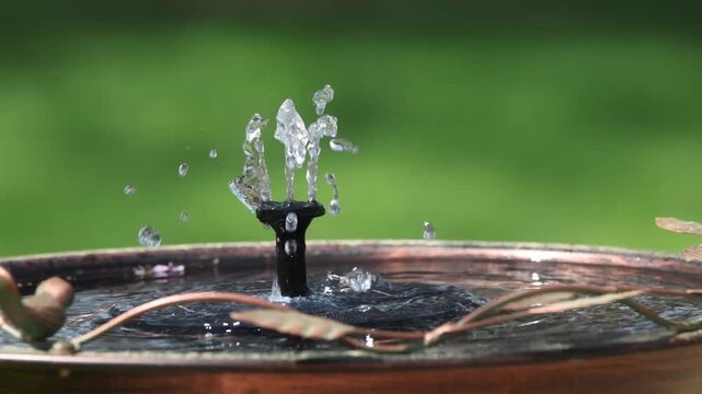 Solar-powered floating water fountain in bronze metallic birdbath. 