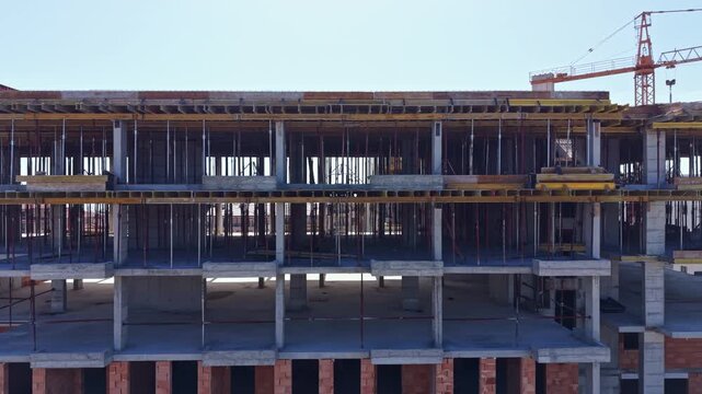 Workers and machinery are busy at a construction site where floors are taking shape in a new building. Steel beams and concrete elements create the structure's framework.