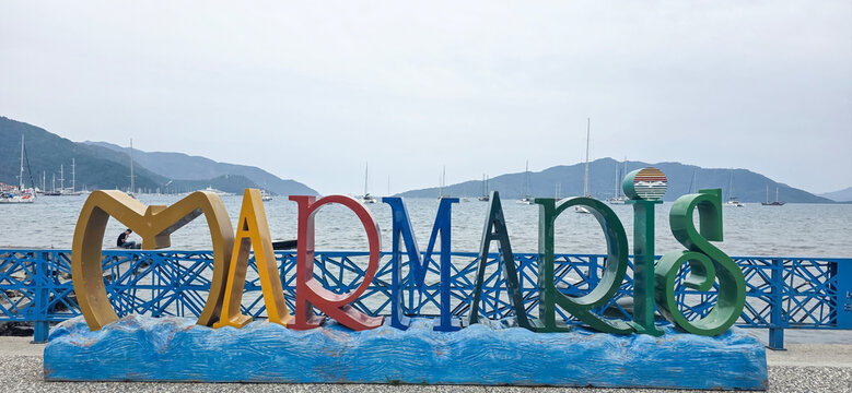 Colorful Marmaris sign by the sea with boats and mountains in background