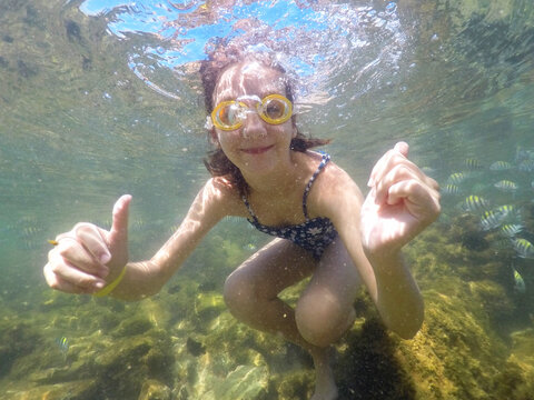 garota mergulha com peixes no mar 