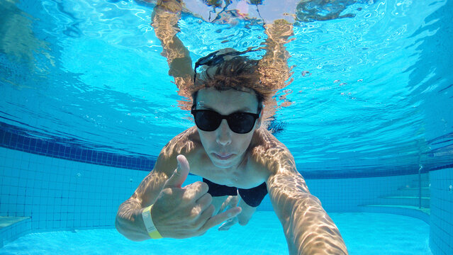 homem nada sub&aacute;quatico em piscina 