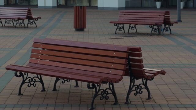 Park bench scene. Serene public square showcasing solitary wooden seat amidst ornate ironwork and patterned paving