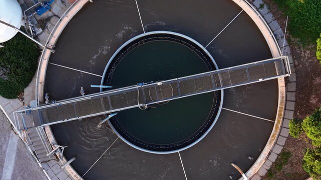 Decentralized wastewater unit with outer aeration ring and inner secondary clarifier, showing turbulent mixing, radial settling, scraper bridge and effluent weir