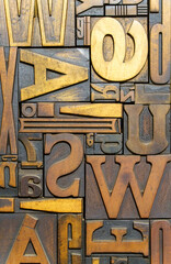 Vintage wooden typesetting letters and blocks for traditional letterpress printing. A close-up background showing old weathered typography stamps with various fonts and characters. © uladzimirzuyeu