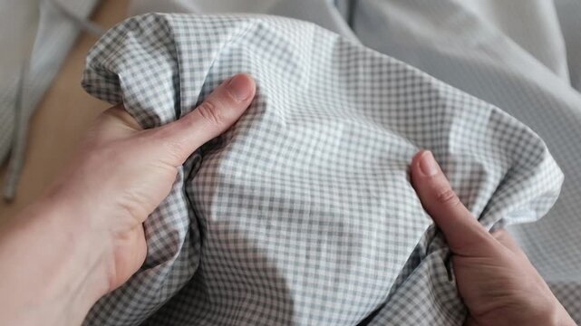 Close-up of soft blue and white gingham fabric texture with gentle folds and ripples. Classic checkered pattern textile background for fashion, home decor, and rustic themes.