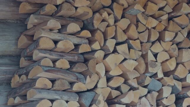 Rough logs stacked against wall. Stacked firewood against aged wooden surface conveying rustic homestead ambiance