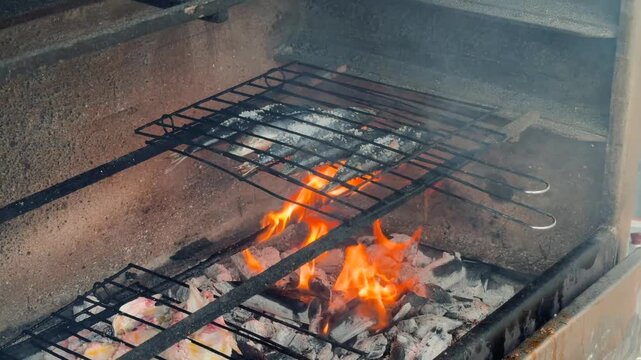 Intense flames engulf meat on open flame barbecue grill