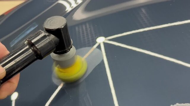 A car service worker polishes the car body with a polishing machine. Detailing and polishing of the car. Car detailing - hands with an orbital polishing machine in an auto repair shop. PDR. 