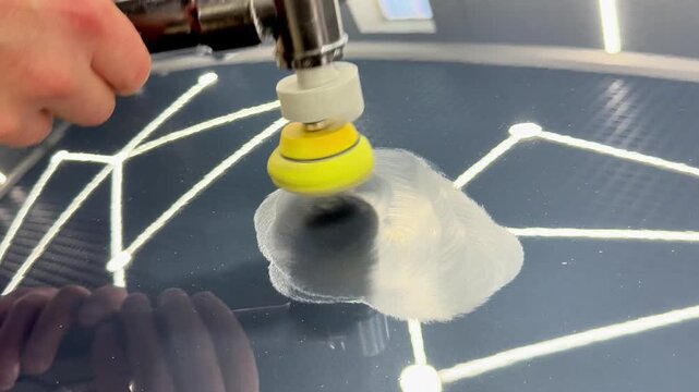 A car service worker polishes the car body with a polishing machine. Detailing and polishing of the car. Car detailing - hands with an orbital polishing machine in an auto repair shop. PDR. 