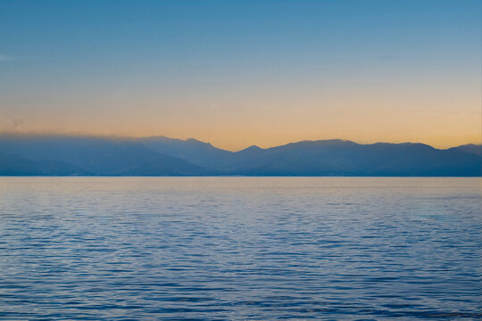 Mer calme bleue avec une cha&icirc;ne de montagnes lointaine sous un ciel de coucher de soleil pastel au large de l'&icirc;le de Capraia, Italie
