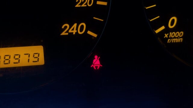 Car dashboard illumination. Nighttime vehicle instrument display. Illuminated dashboard showing speed and warning indicators at night