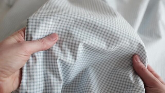 Close-up of soft blue and white gingham fabric texture with gentle folds and ripples. Classic checkered pattern textile background for fashion, home decor, and rustic themes.