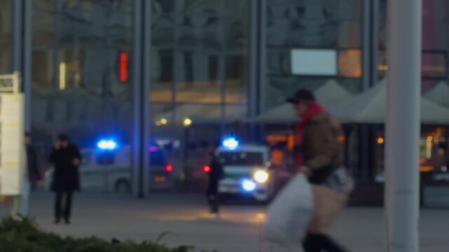 Blue light ambulance reaches city square. Rescue vehicle and police amid rainsoaked reflective pavement scene