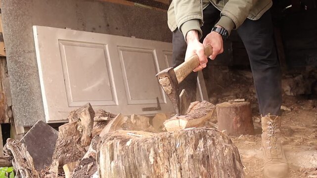 The person strikes the wood with an axe attempting to split it, and a piece suddenly flies into the air, highlighting the unpredictable motion and raw force of manual wood chopping.