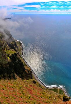 A dramatic, vertical perspective of the towering Cabo Girao cliffs meeting the Atlantic Ocean, evoking a sense of peaceful solitude.