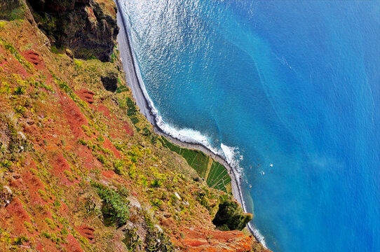 Aerial perspective of the rugged Cabo Girao cliff face in Madeira, overlooking a secluded beach