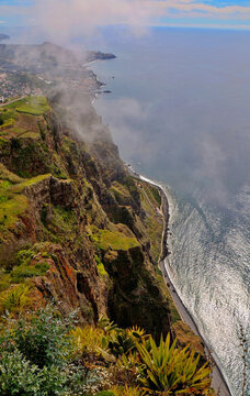 reathtaking vertical perspective of towering cliffs at Cabo Girao in Madeira, shrouded in mist above the vast Atlantic Ocean.