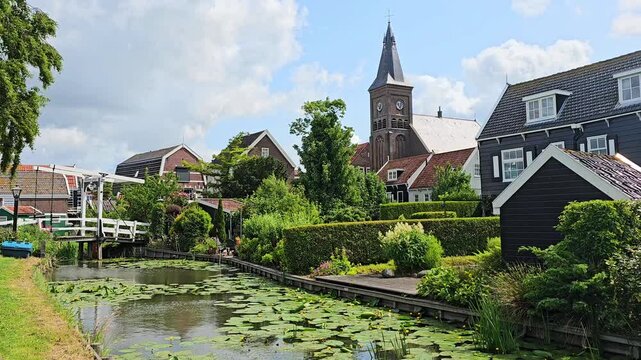Traditional fishing village of Marken, Netherlands. Canal with traditional houses and church. Slow motion.