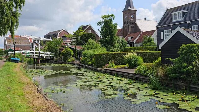 Fishing village of Marken, Netherlands. Walking motion along a picturesque canal lined with traditional houses and church.