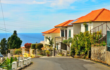 Obraz premium Coastal Houses With Orange Tile Roofs on a Sunny Seaside Street Overlooking the Ocean in Madeira