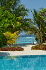 Fototapeta premium Classic Maldives island landscape on a sunny day, coastal luxury resort buildings, azure water, white sand, palm trees on the shore