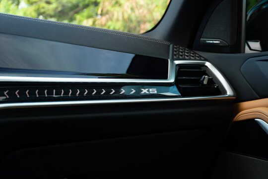 BMW X5 dashboard trim detail close up, luxury SUV cabin illuminated model badge and air vent