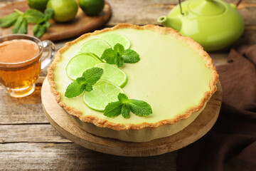 Tasty lime pie with fruit slices and mint leaves on wooden table, closeup © New Africa