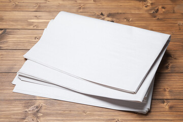 Fototapeta premium Newspapers on wooden table, closeup. Mockup for design