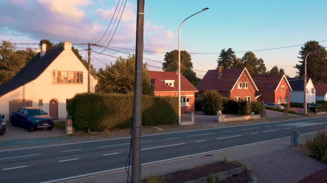 A horizontal view of a street in Europe, showing typical European houses at sunset, with a street in the foreground that has little traffic.