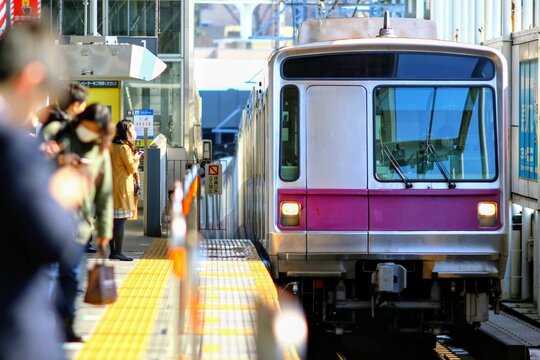 駅のホームに入線する通勤電車と乗客の風景