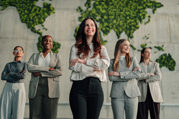 Fototapeta premium Diverse group of businesswomen standing against a green world map, symbolizing global success, empowered leadership, and collaborative team