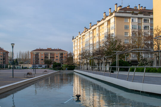 Vista urbana de una plaza con estanque de agua y reflejo de edificios residenciales en Burgos, Espa&ntilde;a