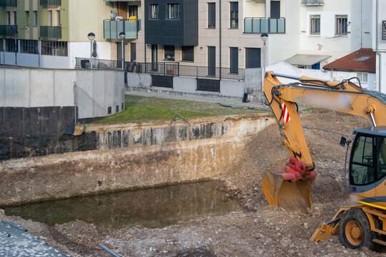 Excavadora trabajando en una zanja con agua durante una obra de construcci&oacute;n urbana en Burgos, Espa&ntilde;a