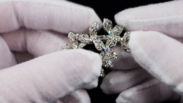 An elegant brooch in the shape of twigs and leaves, adorned with clear crystals and aurora borealis crystals. The silver-tone metal accessory sparkles beautifully under the light.