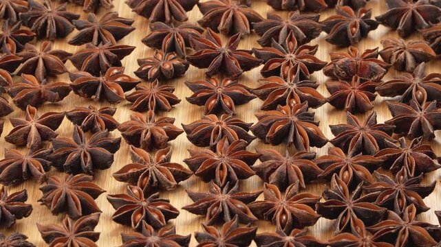 Low angle macro perspective of dried star anise pods on a wooden board. Aromatic spice pattern for Asian culinary, health and wellness projects.